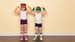 Two children wearing white tank tops, active wear shorts, tube socks, sneakers, and sweat bands. They are ready to exercise. 